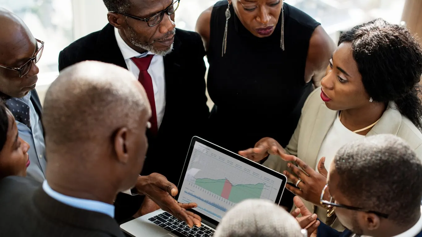 KONNY AFRIQUE team members reviewing financial data together on a laptop