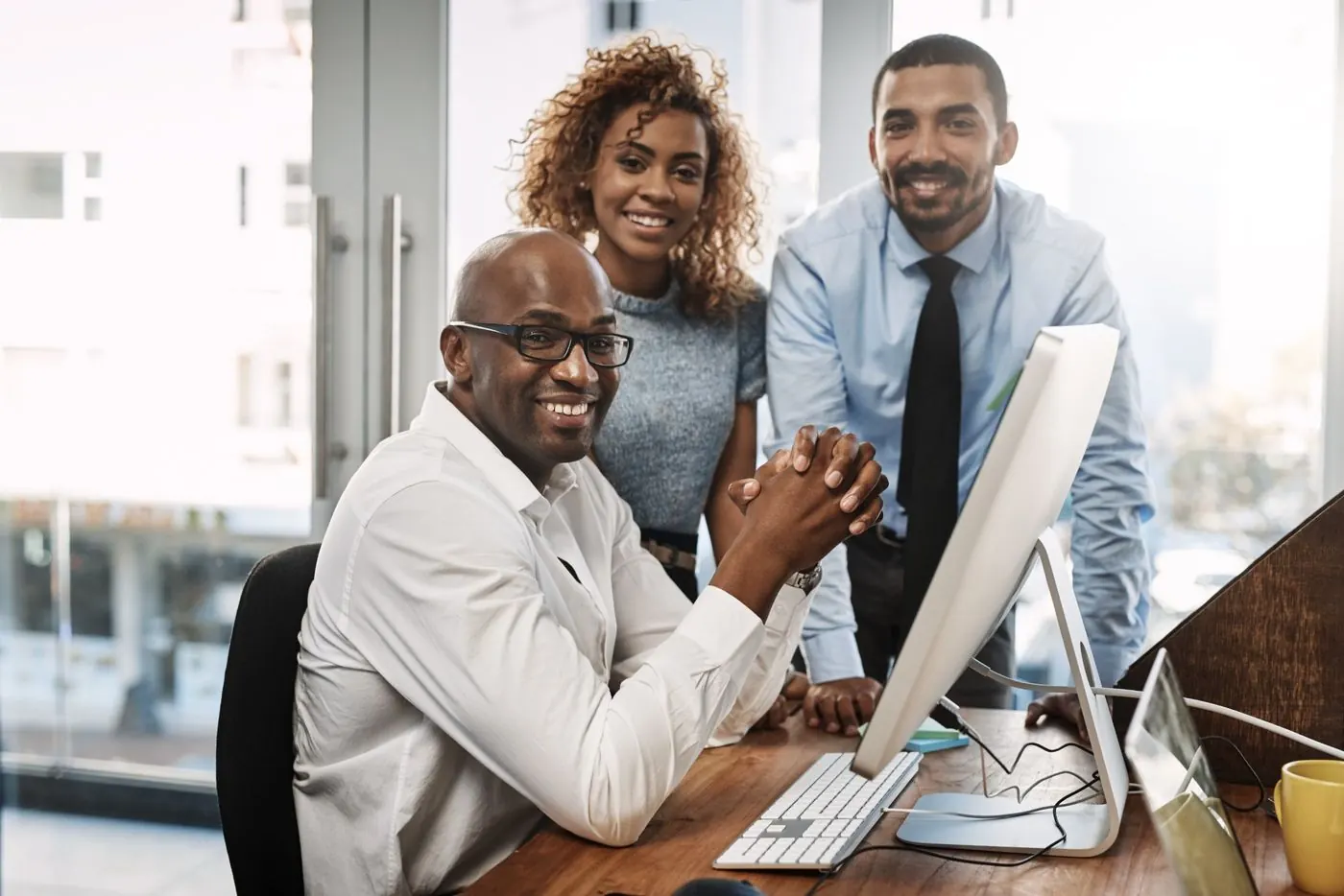 Three smiling KONNY AFRIQUE team members around a workstation